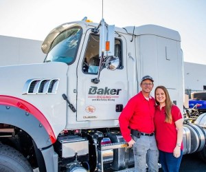Andy and Rebecca Baker standing in front of white semi truck with Baker Rigging logo
